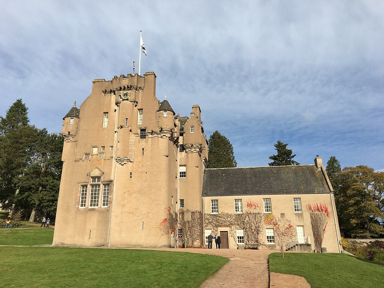 Crathes Castle, a magnificent 16th-century Scottish tower house with turrets and towers, set against rolling green hills